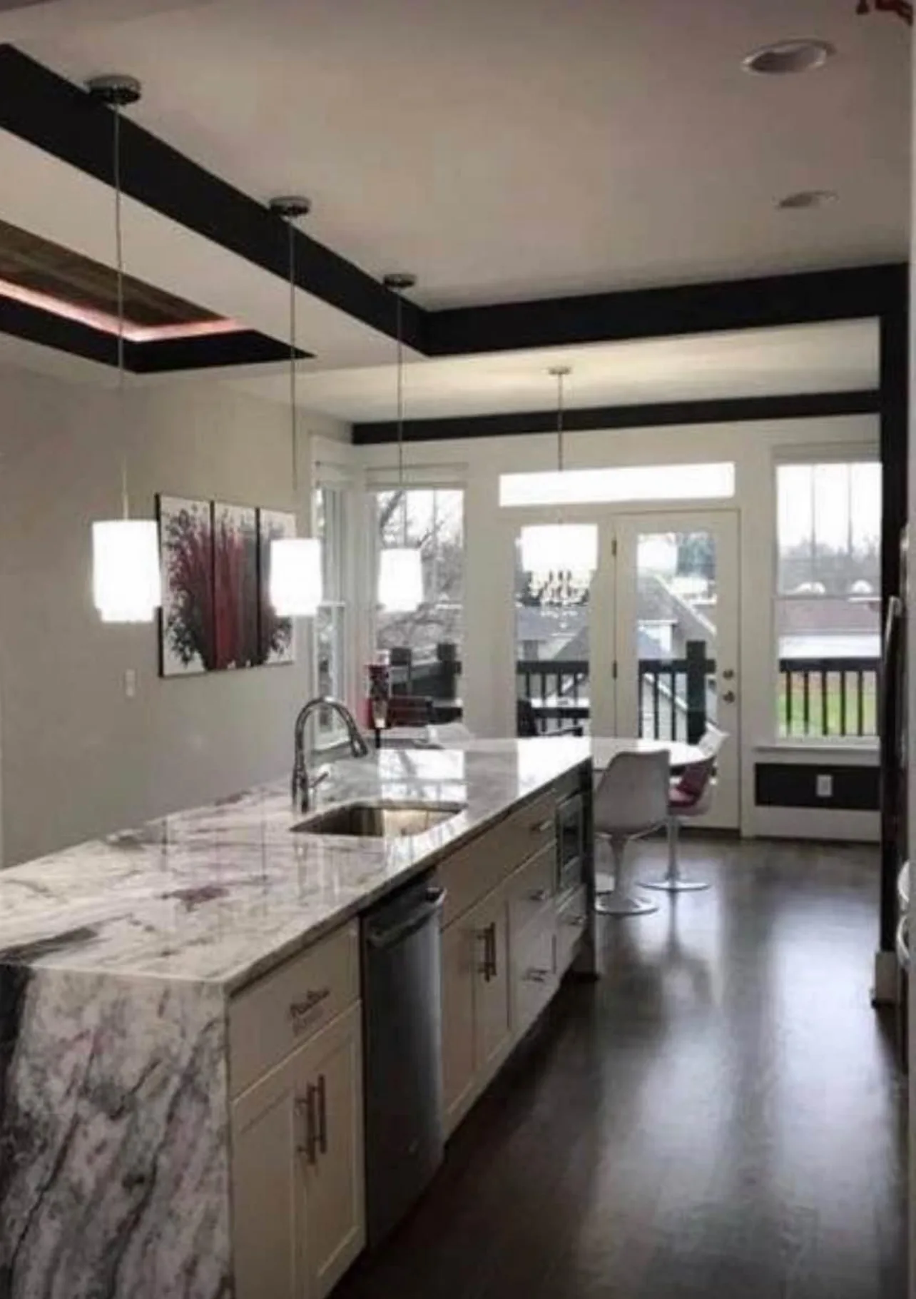 White shaker kitchen with marble waterfall island and coffered ceiling beams