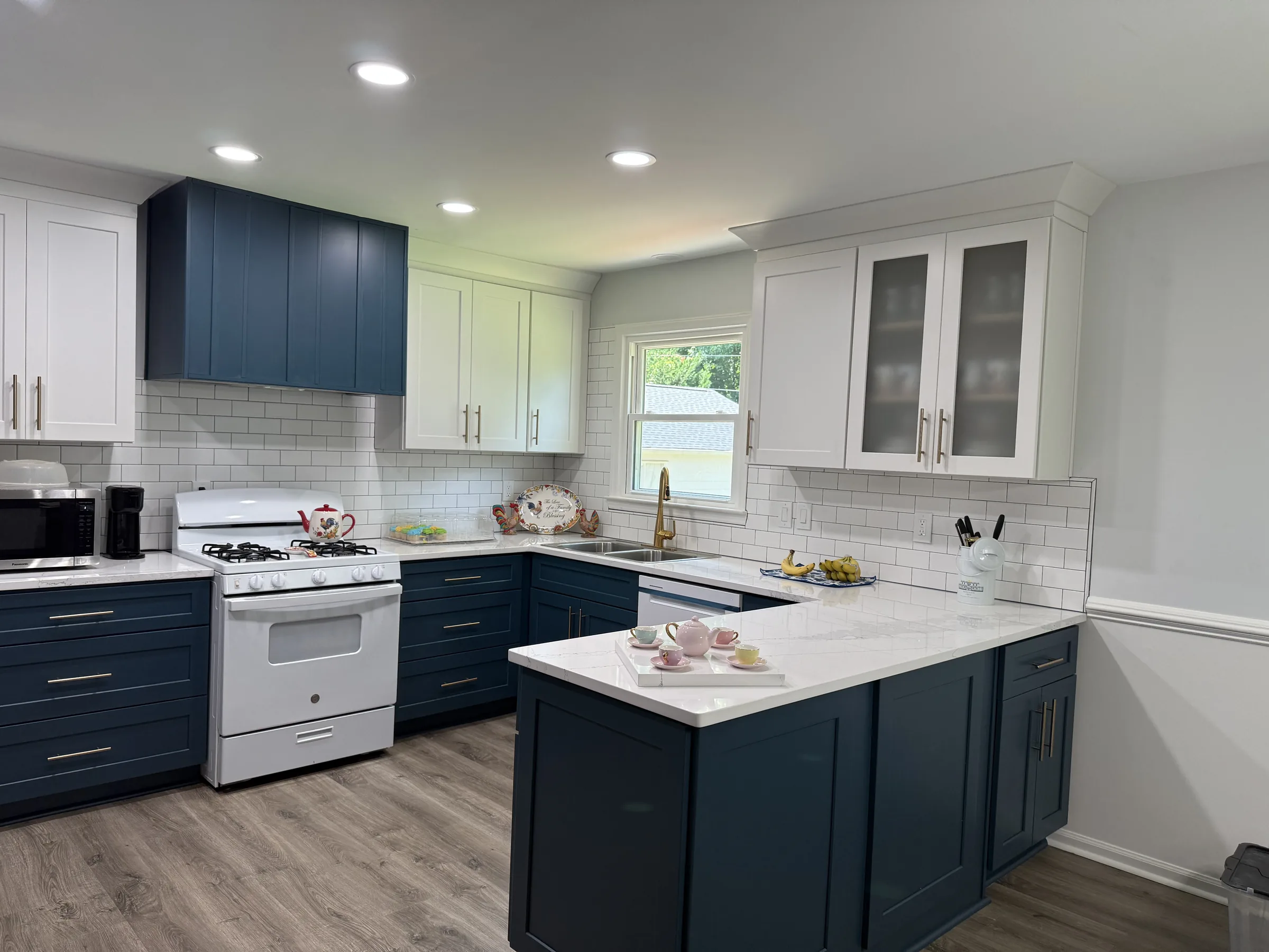 Navy and white two-tone shaker kitchen with gold hardware and quartz peninsula