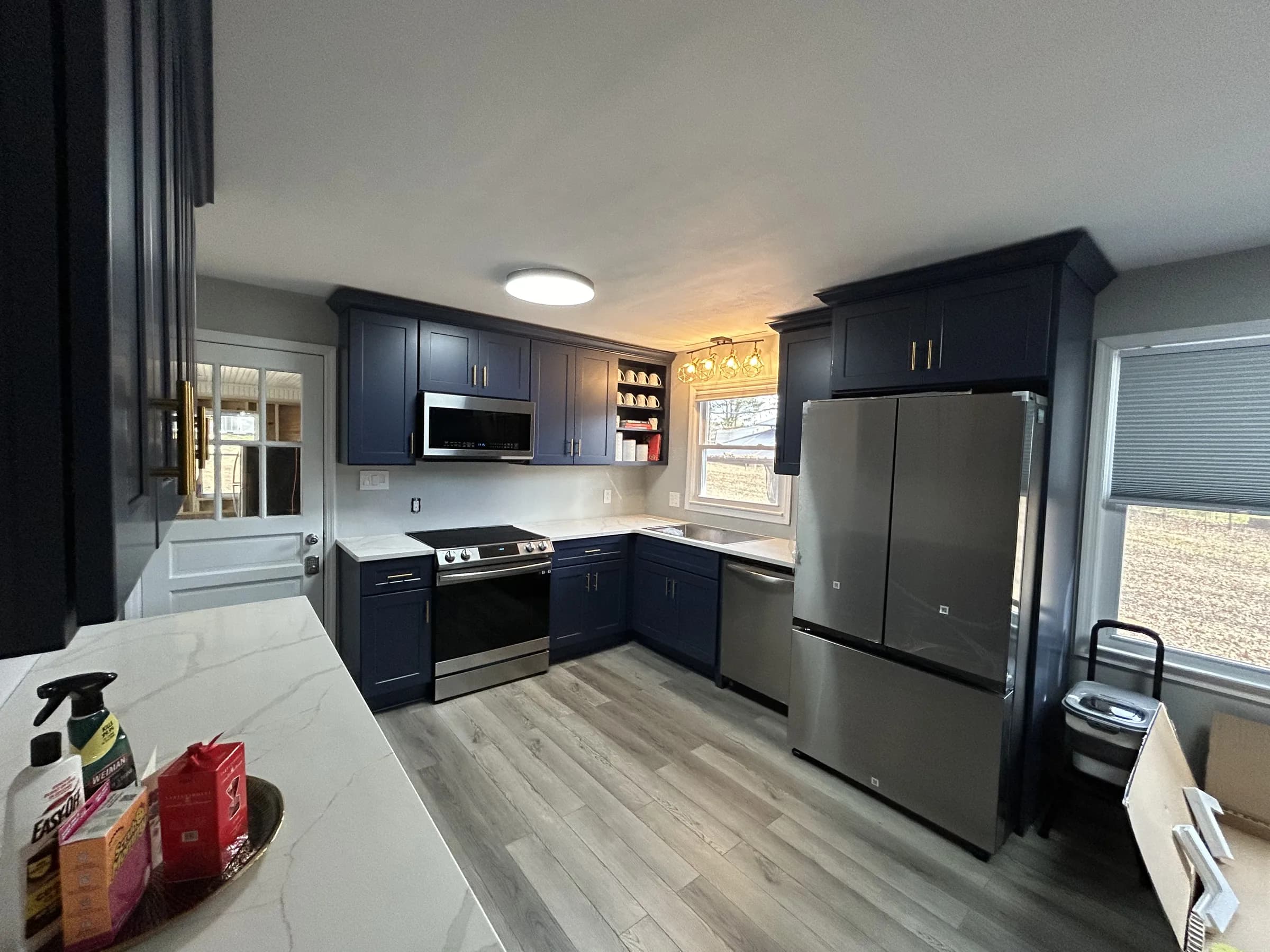 Navy shaker kitchen with white quartz waterfall island and brass pulls