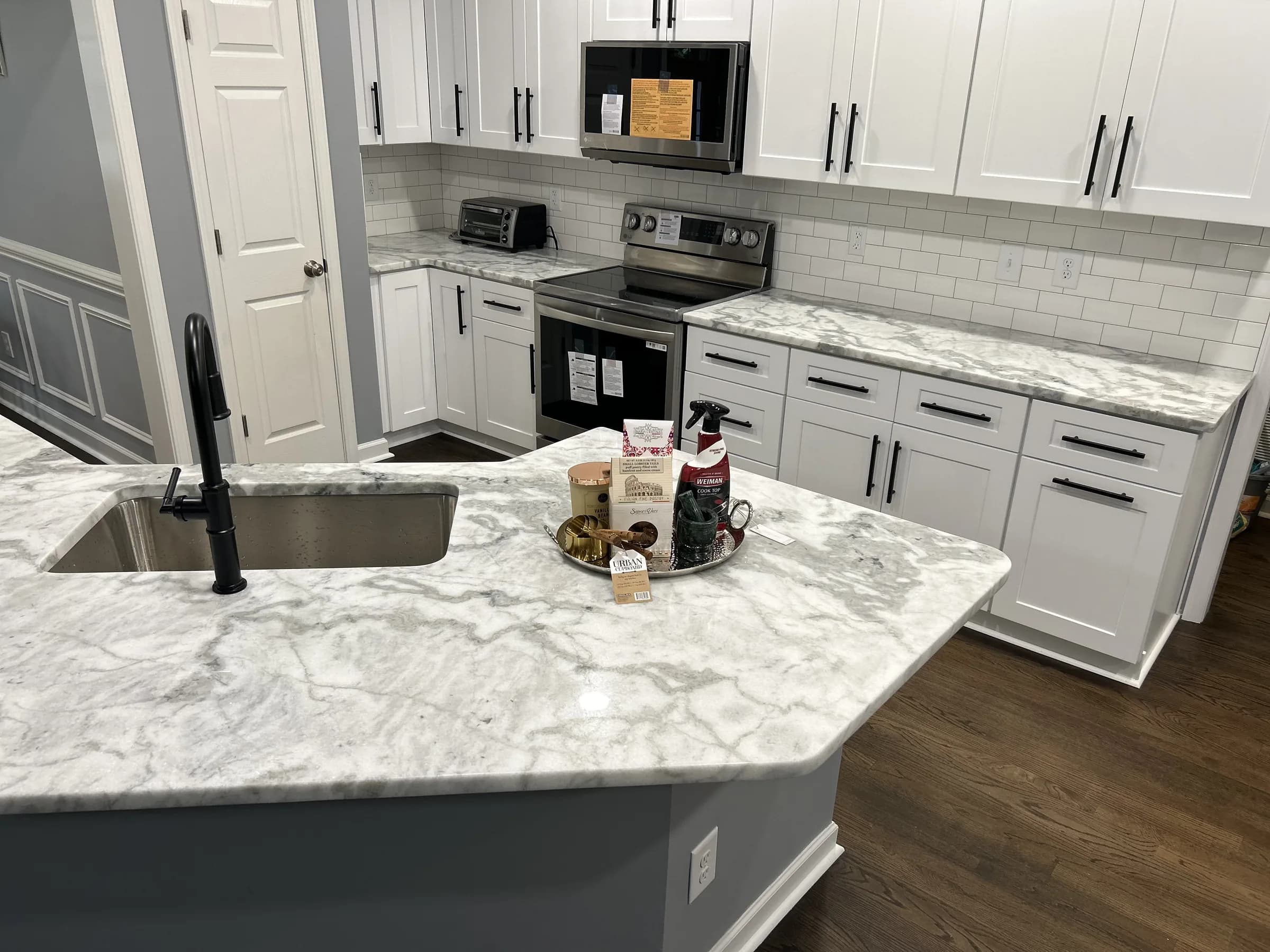 White shaker kitchen with veined marble counters and matte black faucet