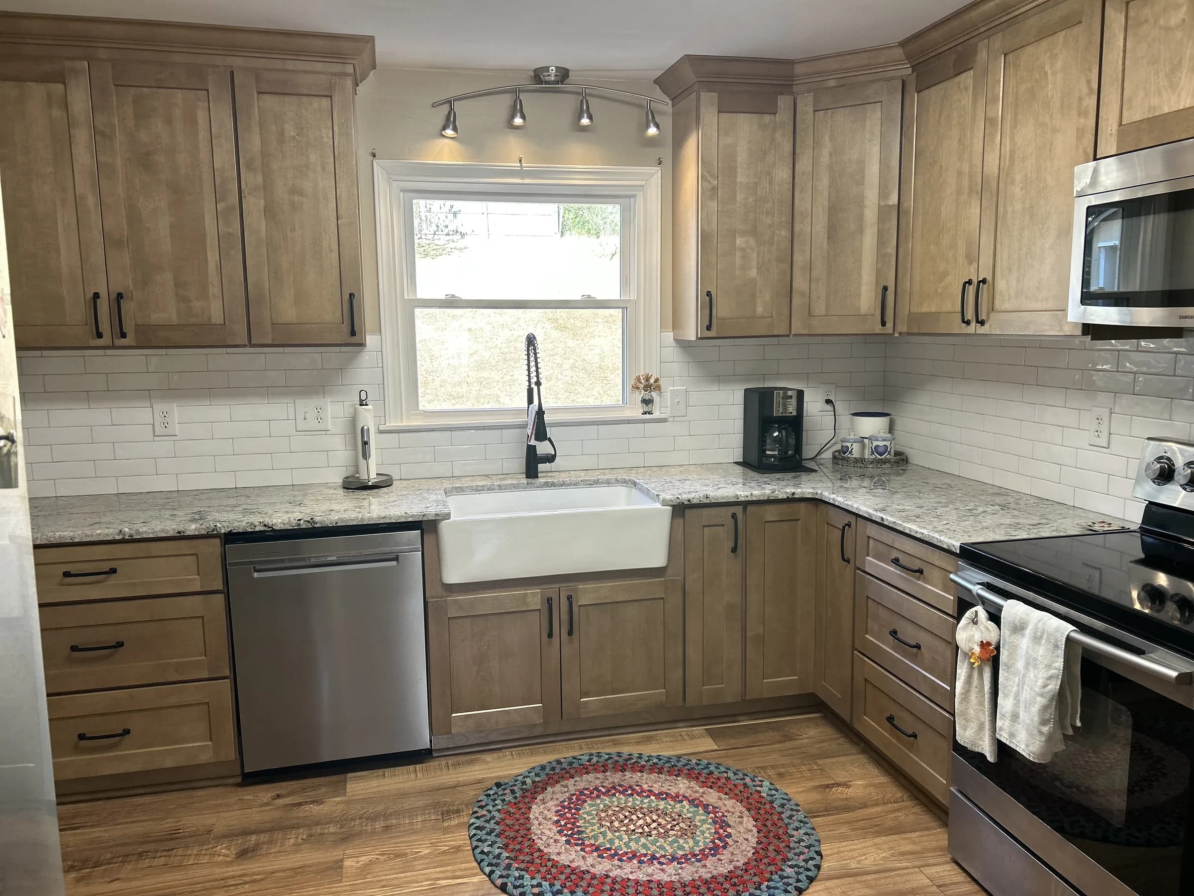 Warm-stained wood shaker kitchen with farmhouse sink and granite counters