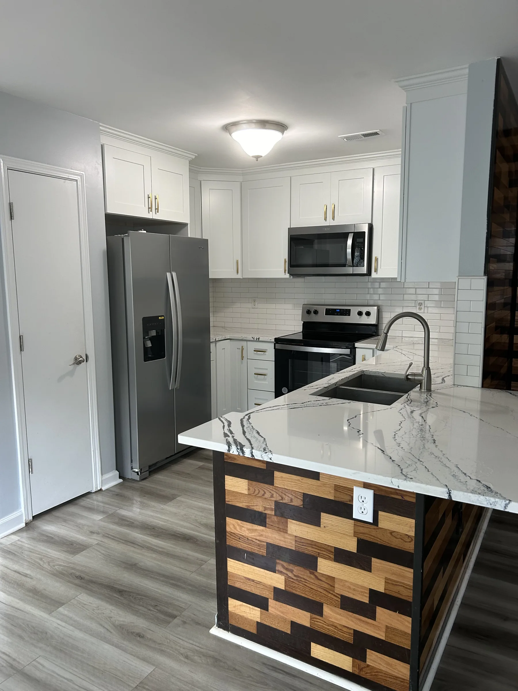 White shaker kitchen with custom geometric wood-block island panel and quartz counter