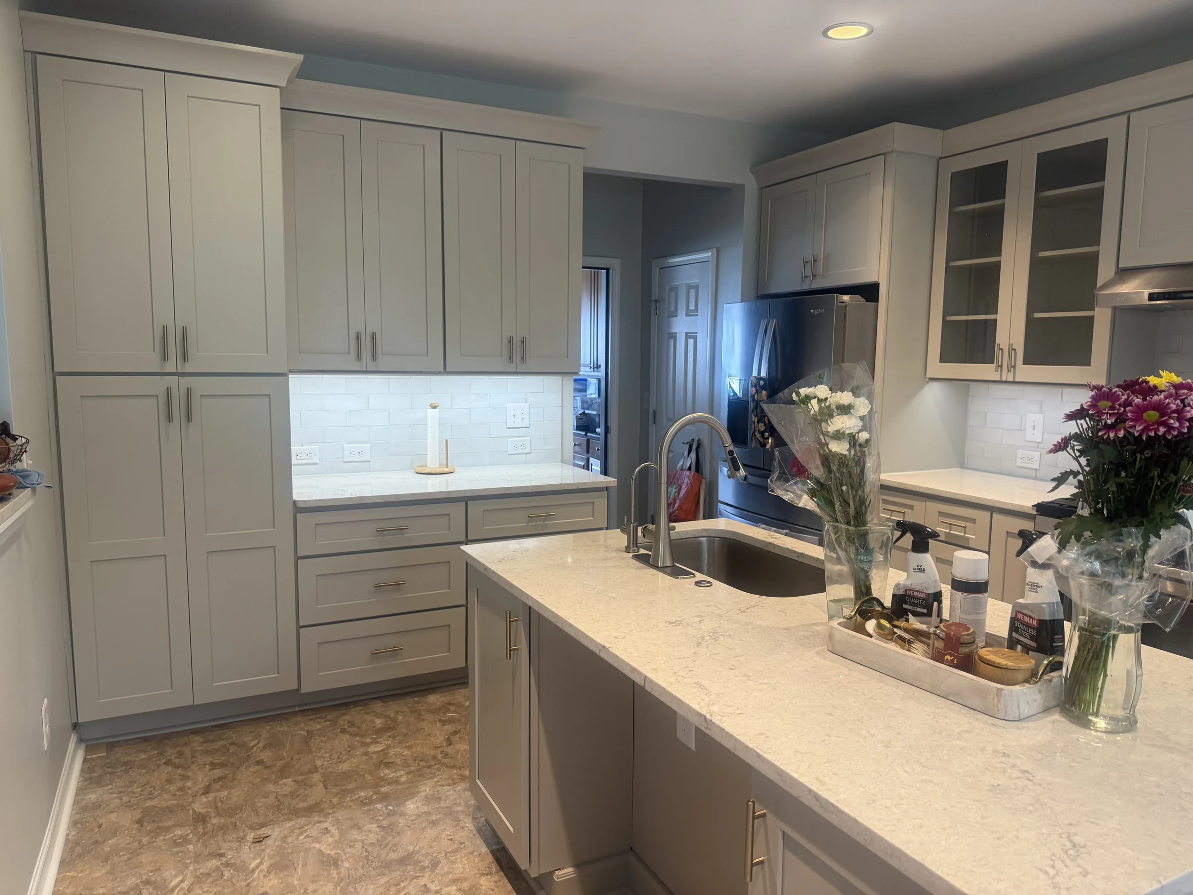 Light gray shaker kitchen with white quartz counters and brass pulls