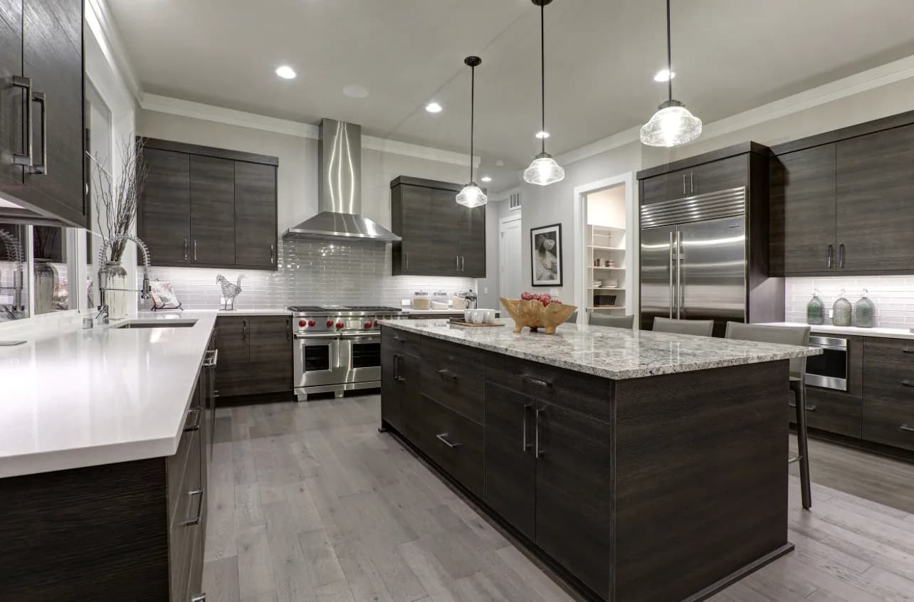 Modern dark slate flat-panel kitchen with white quartz waterfall island and glass pendants