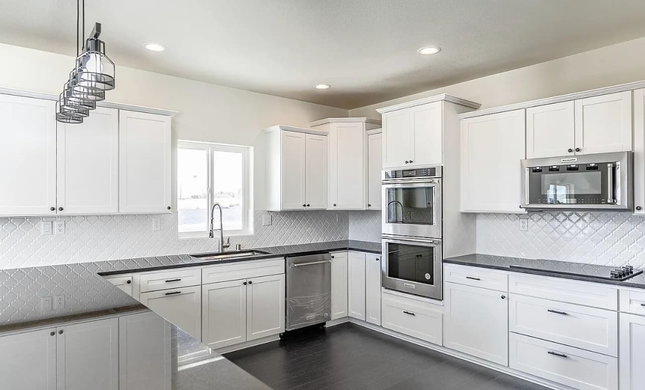 White shaker kitchen with arabesque backsplash and industrial pendant cluster